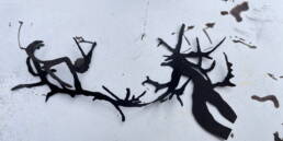 black ink branch forms cut out with black ink spots on paper behind it