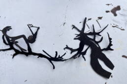 black ink branch forms cut out with black ink spots on paper behind it